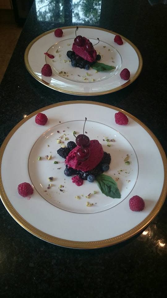 A berry sorbet with blackberries, raspberries and a cherry, on gold-rimmed china