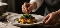 A chef finishing a plated dish with tweezers