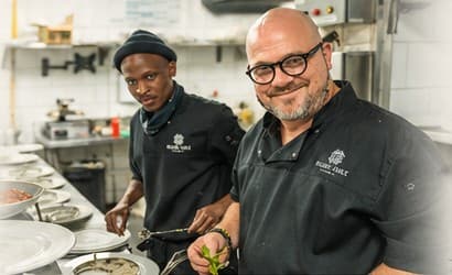 Paul and a fellow chef plating in a busy kitchen