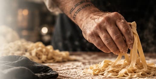 Paul's hand lifting fresh tagliatelle from a floured board