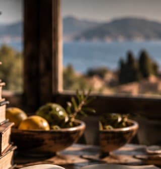 A study window with an olive branch and a bowl of lemons, the sea beyond