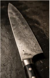 A Damascus chef's knife on a wet dark board