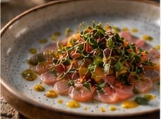 Crudo with citrus and herbs on a speckled plate