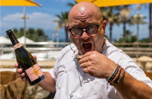 Paul on a sunny terrace, a bottle of rosé in one hand and an oyster in the other