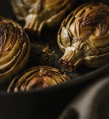 Roasted artichokes in a dark pan