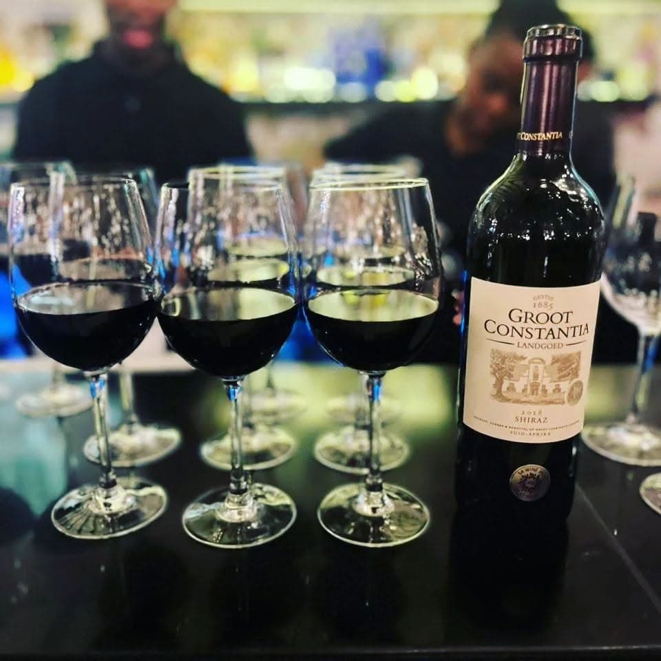 Glasses of red wine poured for a tasting beside the bottle