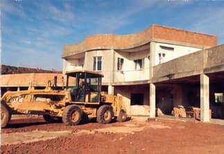 A yellow loader in front of the building on red earth