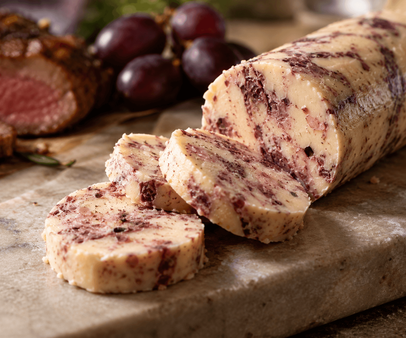 Grape must and shallot compound butter with burgundy marbling, sliced for service.