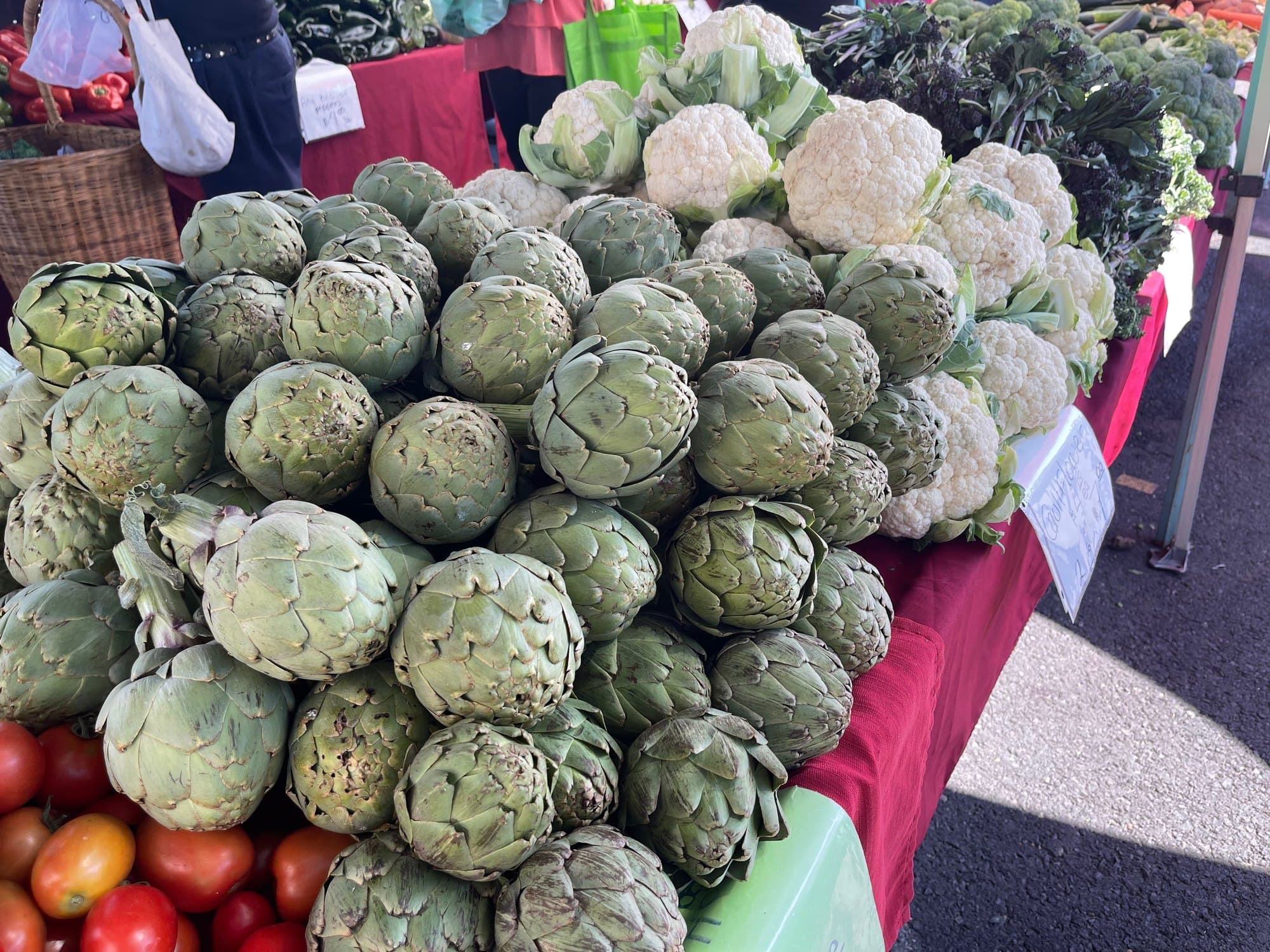 A market display of globe artichokes stacked with their bracts still closed
