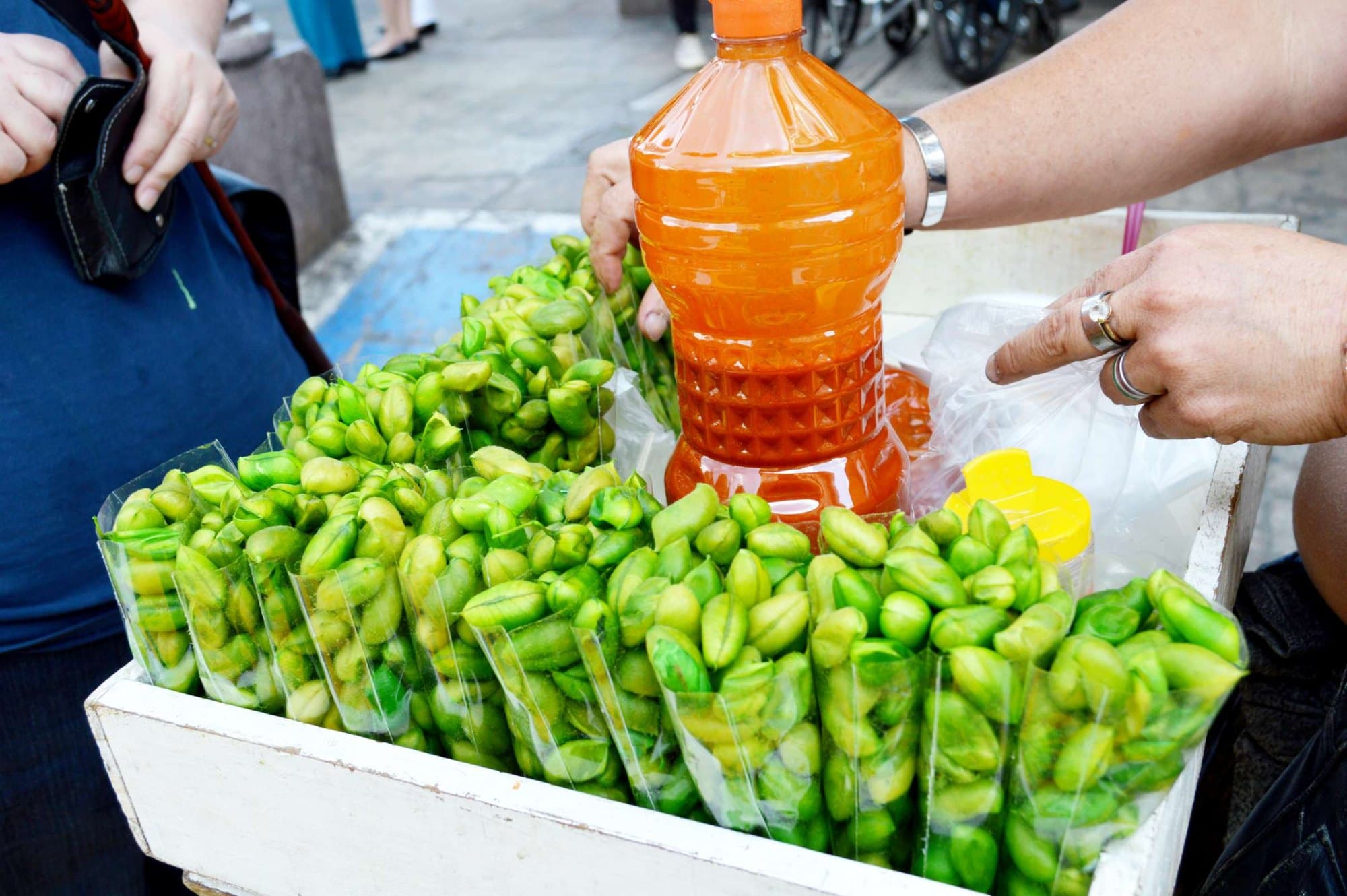 Fresh green chickpeas in their pods sold in bags at a street stall