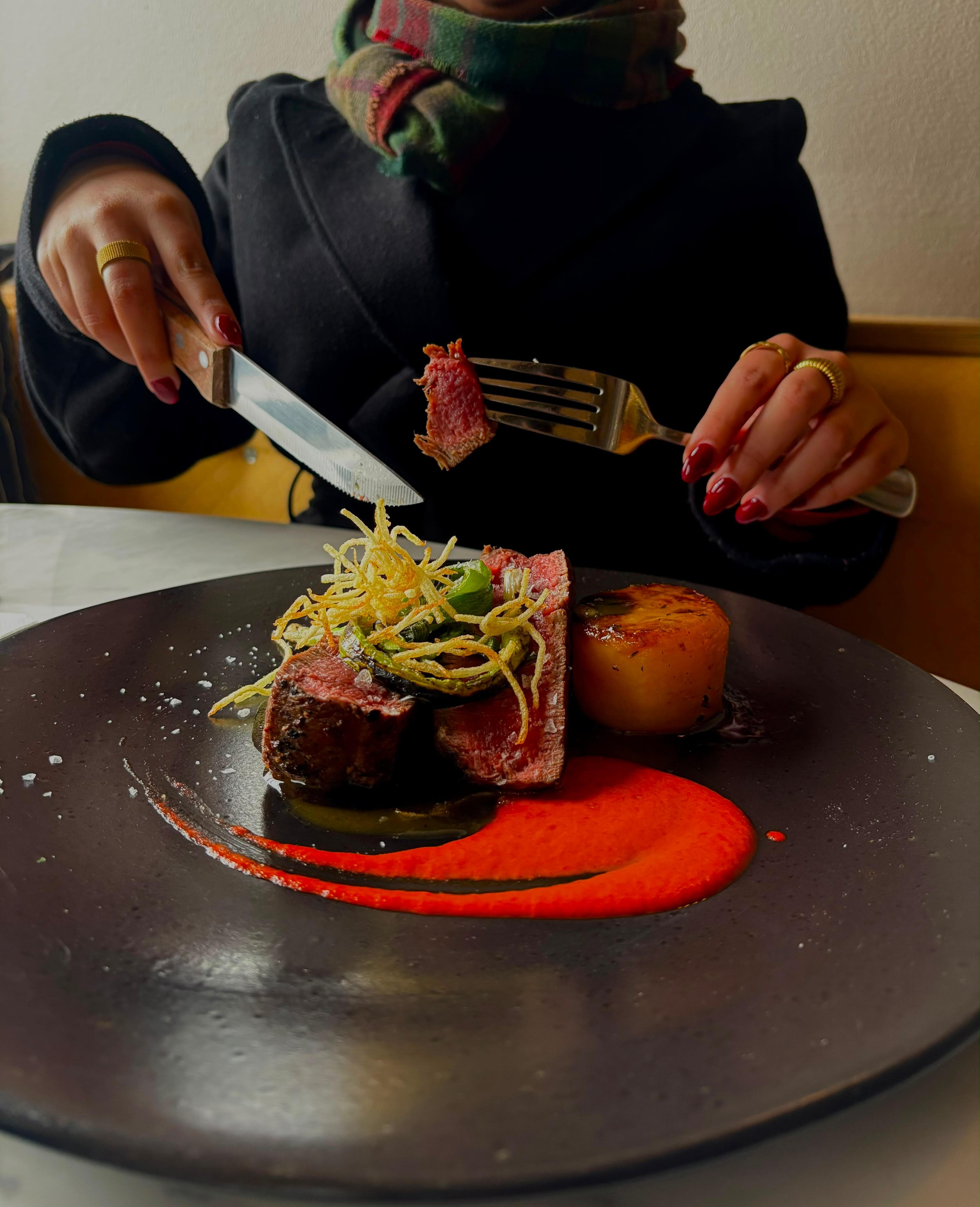 The same dish at the table, a diner lifting a slice of the fillet with a fork