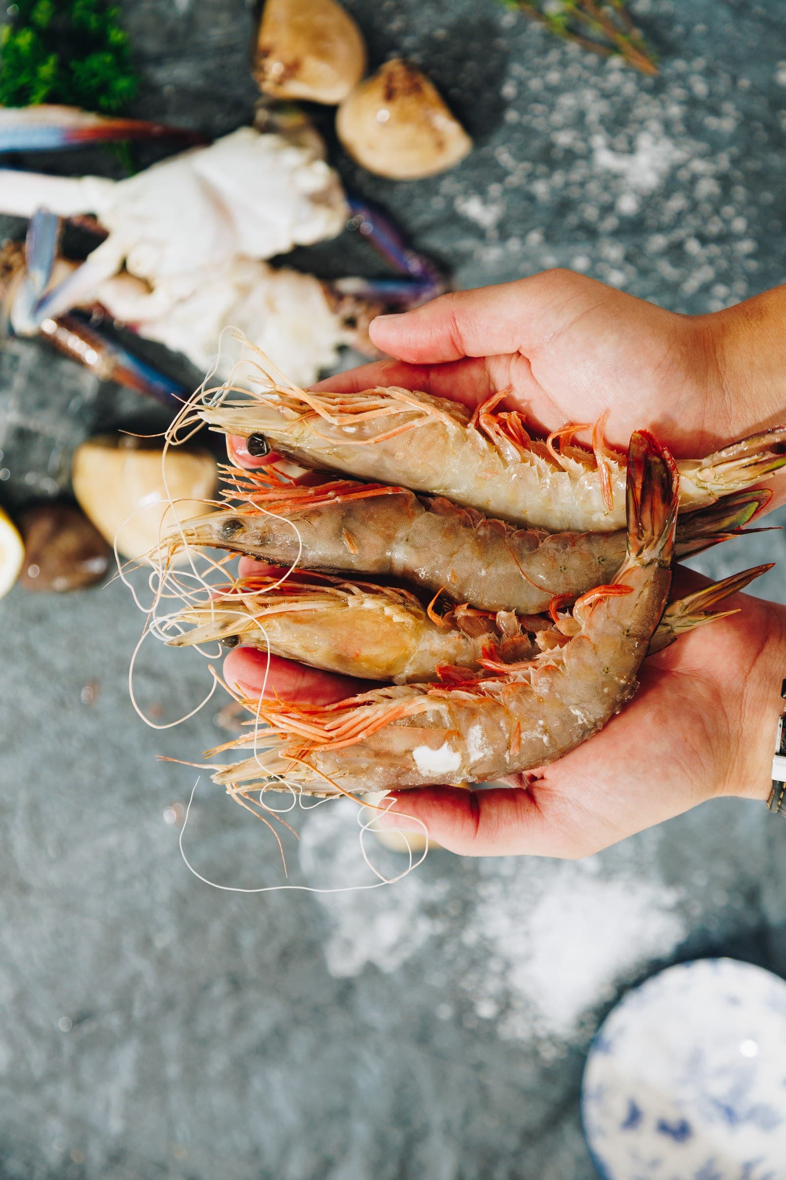 Four large raw prawns held in two cupped hands