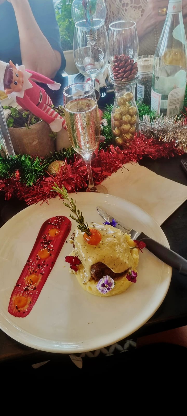 A festive plated dish with flowers and a glass of sparkling wine